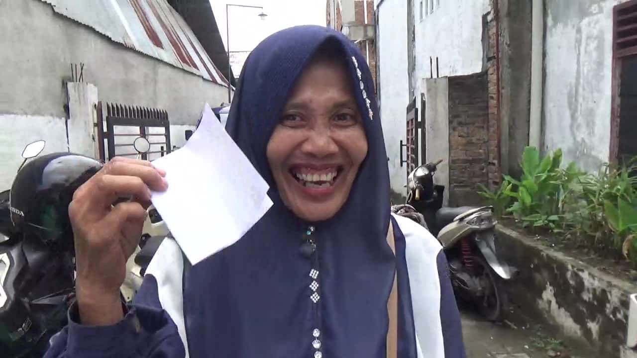 Sulia, warga Marelan, menunjukkan bingkisan dan amplop yang diterimanya usai menghadiri Sosperda Roma Uli Silalahi. Ia mengaku senang mendapatkan informasi seputar perumahan kumuh serta menerima bingkisan berupa botol sirup dan amplop berisi uang, Minggu, 23 Maret 2025, Zeze Futsal, Jalan Marelan Raya, Gang Sepakat, Kelurahan Rengas Pulau, Kecamatan Medan Marelan, Kota Medan (Foto: Dok. seputaranindonesia.com).